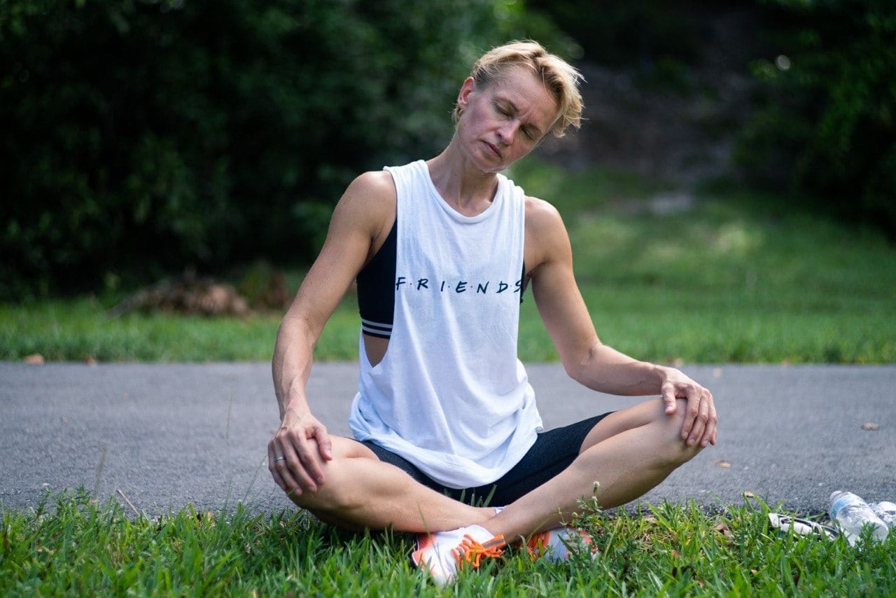 Natalia sitting cross-legged outdoors with her eyes closed